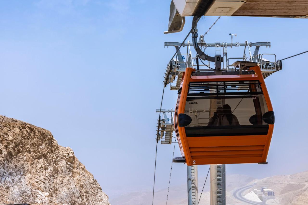 Tolip Resort El Galala Majestic Ain Suchna Exterior foto The photo shows an orange gondola or cable car hanging on a cable system. The gondola appears to be suspended in the air above a rocky landscape, with a clear sky in the background. There are supporting cables and structures visible, indicating that 